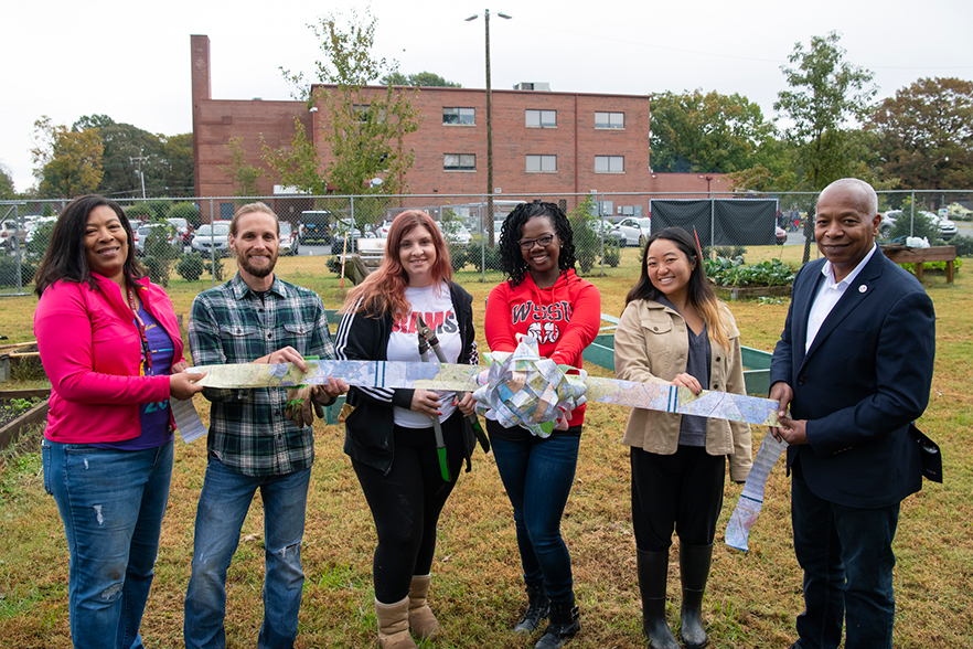 standing with a ribbon inside the community garden