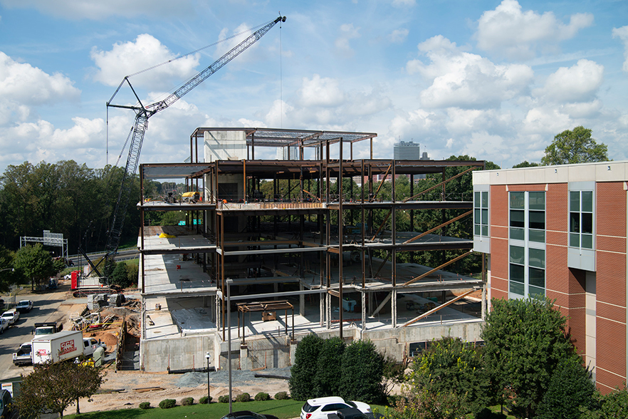 crane at construction site for sciences building, city skyline in background