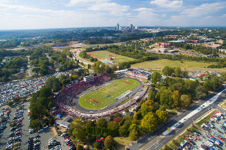 Aerial photo of Bowman Gray Stadium with city's downtown skyline in the background.