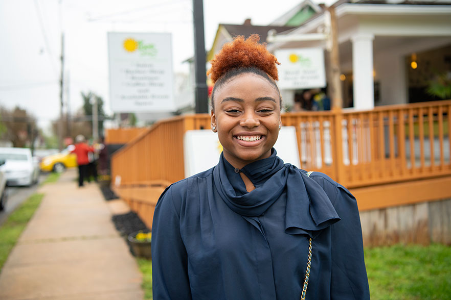 Student stands in front of new signage for 