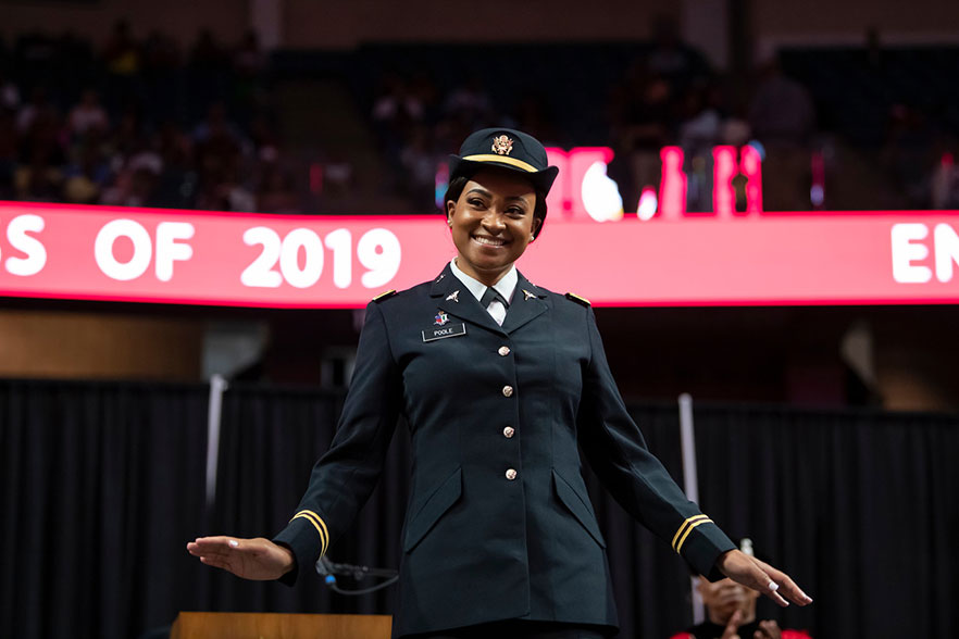 Student stands on stage in uniform